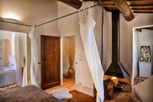 1 dormitorio con 1 cama con cortinas blancas y chimenea en Podere Poggio al sole, en Montepulciano