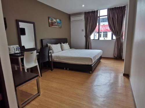 una camera con letto, scrivania e specchio di Padungan Hotel a Kuching