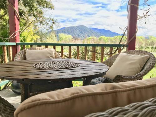 a wooden table and chairs on a porch with a view at Murchison Lodge in Murchison