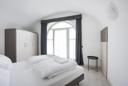 a white bedroom with a large bed and a window at Residence La Vigna in Arco