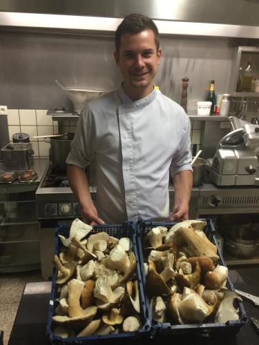 a man in a kitchen holding a tray of mushrooms at Logis Hotel Du Midi in La Roche-en-Ardenne