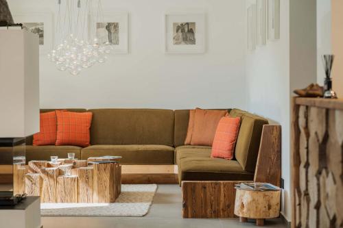 sala de estar con sofá marrón y almohadas de color naranja en Camina Suite and Spa en Cortina dʼAmpezzo