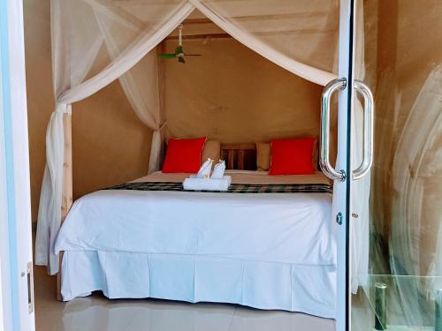 1 dormitorio con cama blanca y almohadas rojas en Sekumpul BnB, en Singaraja