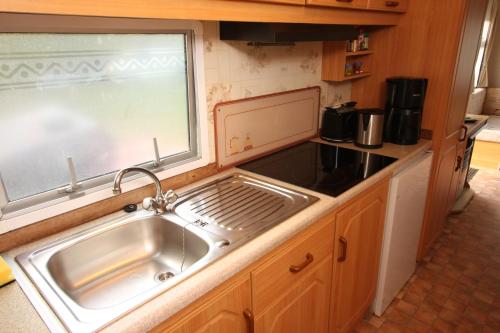 a kitchen with a stainless steel sink and a window at Mobilhome Markgrafenheide für Familie und Monteure in Markgrafenheide