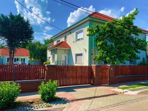 a house with a wooden fence in front of it at Airport Jazmin Guesthouse in Vecsés