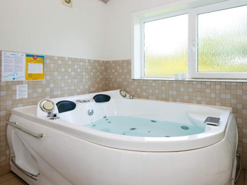 uma banheira branca na casa de banho com uma janela em 8 person holiday home in Tarm em Hemmet