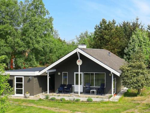 une petite maison noire avec des chaises sur la terrasse couverte dans l'établissement 7 person holiday home in Hals, à Hals