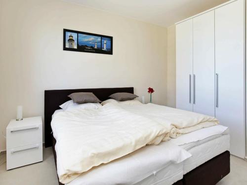 een slaapkamer met een groot wit bed met een zwart hoofdeinde bij Two-Bedroom Holiday home in Großenbrode 15 in Großenbrode