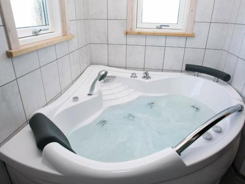 Three-Bedroom Holiday home in Brovst 31 في Brovst: حوض استحمام مملوء بالماء الأزرق في الحمام