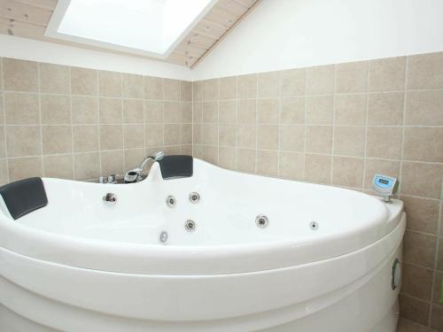a white bath tub in a bathroom with a skylight at Three-Bedroom Holiday home in Løkken 40 in Løkken