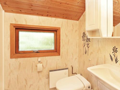 baño con aseo y lavabo y ventana en Three-Bedroom Holiday home in Idestrup 3, en Bøtø By