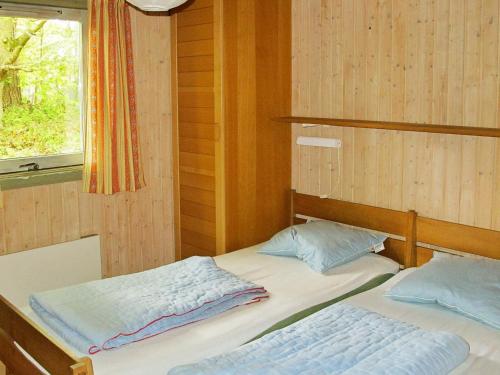 two twin beds in a room with a window at Four-Bedroom Holiday home in Væggerløse 18 in Marielyst