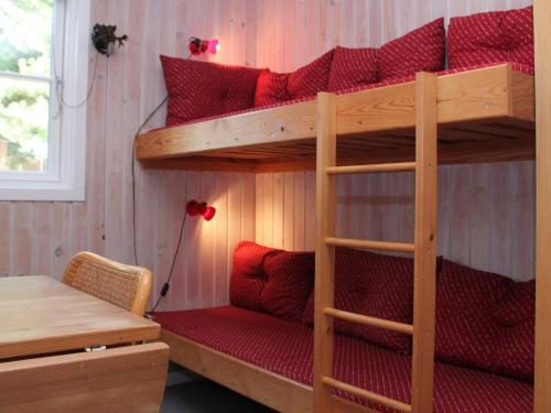 um quarto com 2 beliches e almofadas vermelhas em Three-Bedroom Holiday home in Vejby 14 em Blåvand