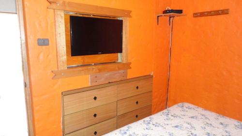 a bedroom with a dresser with a television and a window at Cabañas Aires del Bosque in Concón