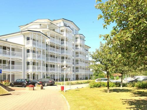 un grand bâtiment blanc avec des voitures garées dans un parking dans l'établissement 4 person holiday home in Gro enbrode, à Großenbrode