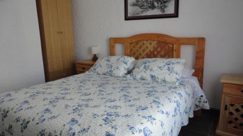 a bedroom with a bed with a blue and white comforter at Cabañas Aires del Bosque in Concón