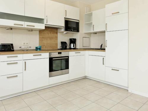 eine weiße Küche mit weißen Schränken und Geräten in der Unterkunft 4 person holiday home in Gro enbrode in Großenbrode