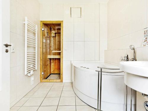 ein Badezimmer mit einer Badewanne, einem Waschbecken und einer Tür in der Unterkunft 4 person holiday home in Gro enbrode in Großenbrode