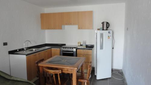 a kitchen with a white refrigerator and a table at Cabañas Aires del Bosque in Concón