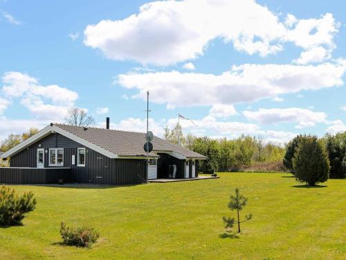 a black house in a field with a green yard at 6 person holiday home in Hadsund in Øster Hurup