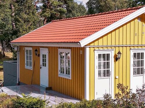 een gele en witte schuur met een rood dak bij 4 person holiday home in VIKBOLANDET in Arkösund