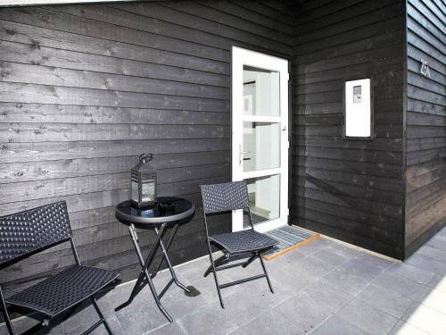 a patio with two chairs and a table and a window at 10 person holiday home in Bl vand in Blåvand