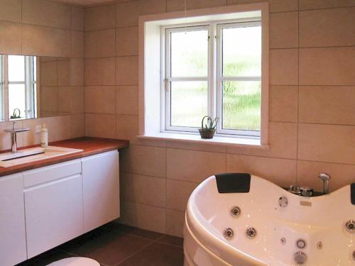 bagno con vasca, lavandino e finestra di 6 person holiday home in Allinge ad Allinge