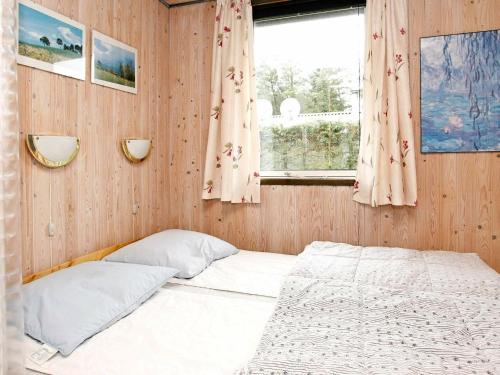 een kleine slaapkamer met een bed en een raam bij Three-Bedroom Holiday home in Løkken 41 in Grønhøj