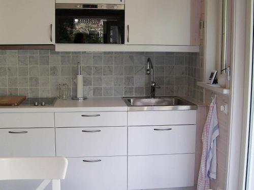 een keuken met witte kasten en een wastafel bij One-Bedroom Holiday home in Kållekärr in Apelgården