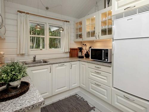 La cuisine est équipée de placards blancs et d'un réfrigérateur blanc. dans l'établissement 6 person holiday home in L s, à Læsø