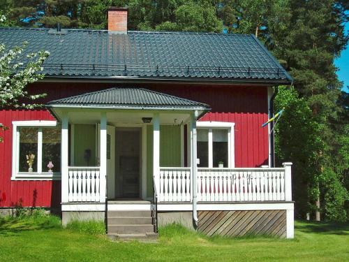 a red house with a white porch and a white fence at 5 person holiday home in ARVIKA in Arvika