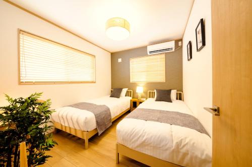 ein Zimmer mit 2 Betten und einer Pflanze darin in der Unterkunft FUJI-AKATSUKI Enn in Fujikawaguchiko