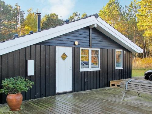 a black shed with a white door and a bench at 6 person holiday home in R dby in Rødby