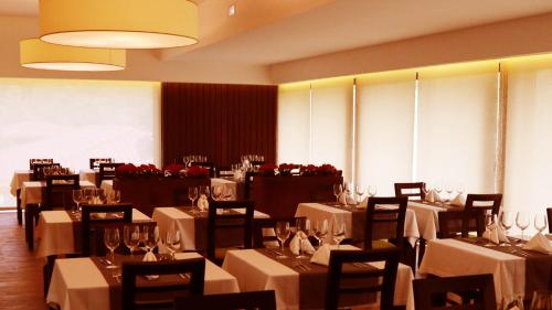 a dining room with tables and chairs with white tablecloths at Agrinho Suites & Spa Gerês in Valdosende