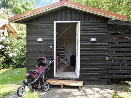 a black shed with a stroller in front of it at 6 person holiday home in Nyk bing Sj in Højby