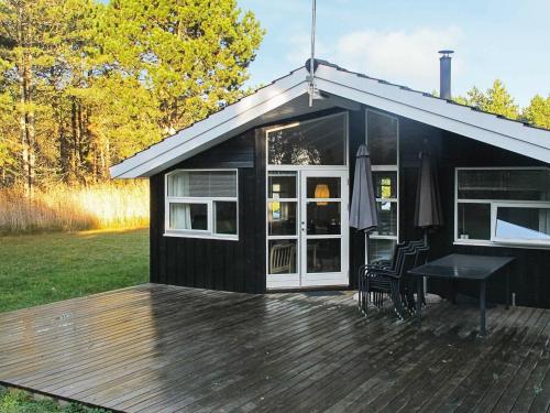 a black shed with a deck and a table at 6 person holiday home in R dby in Rødby