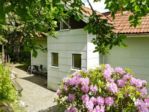 una casa blanca con flores rosas delante en 6 person holiday home in Brastad en Brastad