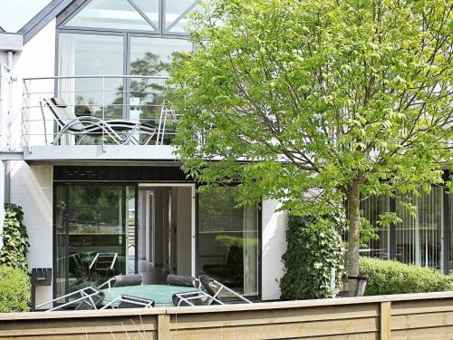 ein Glashaus mit einer Terrasse und einem Baum in der Unterkunft 4 person holiday home in V ggerl se in Bøtø By
