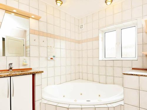 biała łazienka z wanną i oknem w obiekcie 8 person holiday home in Bl vand w mieście Blåvand