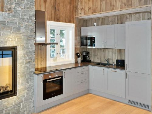 a kitchen with white cabinets and a stone wall at 5 person holiday home in F vang in Favang