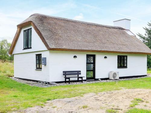 a white cottage with a thatched roof and a bench at 7 person holiday home in Fjerritslev in Torup Strand