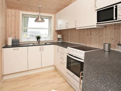 a kitchen with white cabinets and a black counter top at 6 person holiday home in Hirtshals-By Traum in Hirtshals