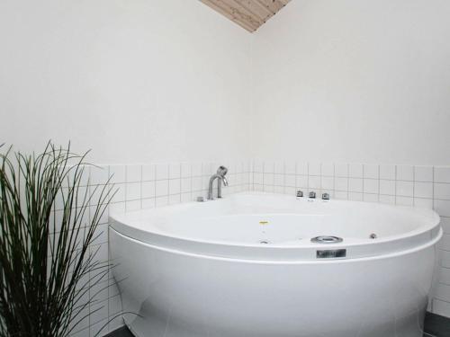 eine weiße Badewanne in einem weißen Badezimmer mit einer Pflanze in der Unterkunft 6 person holiday home in Hirtshals-By Traum in Hirtshals