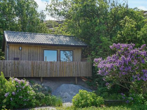 a small wooden house with a fence and purple flowers at 3 person holiday home in R nn ng in Rönnäng
