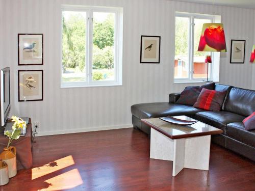 a living room with a black leather couch and a table at 5 person holiday home in S DER KRA in Söderåkra