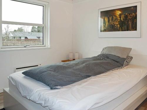 een bed in een witte kamer met een raam bij Holiday Home Brøndbækken II in Nørre Hurup