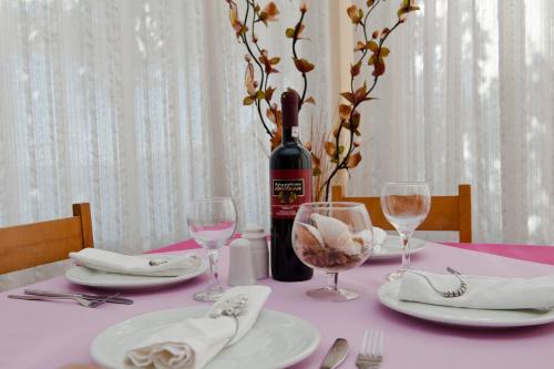 a pink table with a bottle of wine and glasses at Hotel Solon in Tolo