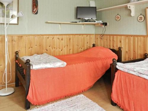 a bedroom with two beds and a tv on the wall at Holiday Home Västra IV in Lysekil