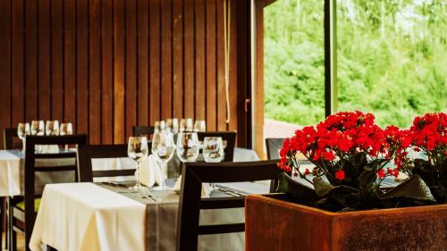 a dining room with a table with red flowers and glasses at Agrinho Suites & Spa Gerês in Valdosende