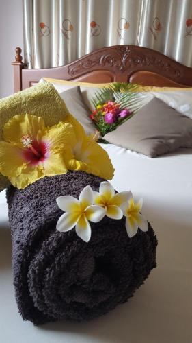 Una cama con flores amarillas y blancas. en Aux plaisirs de la vie, en Flic en Flac